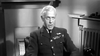 A stern white-haired man in uniform sits and speaks in black-and-white, medals on his jacket, capturing the inspiring WWII biopic style of "Reach for the Sky (1956) DVD," based on RAF hero Douglas Bader's story.