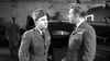 Two men in military uniforms face each other in a hangar, an aircraft behind them, capturing the tension and heroism of the RAF as portrayed in Reach for the Sky (1956) DVD.