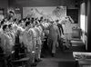 A group of men in military uniforms stands in a classroom as officers enter and salute. Sunlight streams through windows onto a world map, all depicted in "The Wild Blue Yonder (1951) DVD.