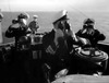 Four naval officers in uniform scan the horizon on a ship’s bridge in calm seas during WWII. Morning Departure (1950) DVD captures this tense submarine drama—essential viewing for classic movie fans.