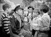 A man in a pilot’s uniform and leather jacket sits with four children and a woman outdoors, evoking classic films like "A Guy Named Joe (1943)" DVD, as they engage in lively conversation and attentive listening.