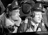 Two pilots in uniform and leather jackets sit side by side in a cockpit, evoking scenes from classic films like A Guy Named Joe (1943) DVD, recalling Spencer Tracy’s iconic style with a sheepskin-collared jacket.