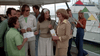 A group of people gather on a docked boat, chatting and smiling with tickets in hand. Boats and colorful pennant flags fill the background as they prepare to watch Empire of the Ants (1977) on DVD, evoking classic sci-fi horror movie vibes.