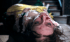 A woman in period costume lies at the foot of a staircase, face scratched and bloodied, looking distressed in this dark, dramatic scene from The Ugly Stepsister DVD.