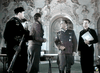 Several men in WWII-era uniforms stand and talk in an ornate room; one holds a rifle, another papers. The scene recalls classic espionage films like Decision Before Dawn (1951) DVD.