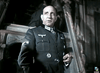 A man in a dark Nazi uniform with medals stands indoors, evoking WWII espionage drama. The scene recalls the tension of classic films like "Decision Before Dawn (1951)" available on DVD.