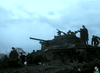 Silhouetted soldiers surround a tank on muddy ground beneath a cloudy sky, capturing the tense WWII atmosphere found in the classic film Decision Before Dawn (1951) on DVD.