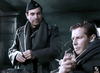 Two men in military uniforms are indoors—one standing, one seated with a glass and cigarette. The dim, serious scene recalls classics like Decision Before Dawn (1951) DVD.