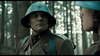 A soldier in a brown uniform and blue helmet stands in a sunlit forest, locked in a tense moment—an iconic scene from the acclaimed World War II film "April 9th (2015)," now available as a rare DVD.