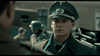 A man in uniform stands outdoors, looking serious, with soldiers behind him in this gripping World War II film. April 9th (2015) DVD captures intense moments of wartime courage and camaraderie.