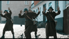 Three soldiers in brown uniforms and blue helmets raise their hands in surrender on a cobblestone street—a dramatic moment from the World War II film April 9th (2015) DVD, with military gear scattered around them.