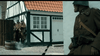 Three soldiers in brown uniforms and helmets stand by a half-timbered house amid swirling smoke, as subtitles read "Sir, we're out of ammo"—a tense moment from the World War II film April 9th (2015) DVD.