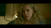 A woman with long, wavy blonde hair and gold hoop earrings gazes thoughtfully to the side in dim light, evoking a scene from The House That Jack Built (2018) DVD.