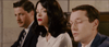 Three people in formal wear—two men in suits and glasses beside a dark-haired, red-lipped woman—sit together as if at a screening of The Pardon (2013) DVD.