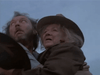 Two older adults wearing hats embrace under a pale sky, their anxious expressions recalling the emotional depth of rare classic movies available on DVD like Winds of Autumn (1976).