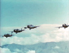 Four vintage military planes fly in formation over clouds and mountains under a blue sky, echoing dramatic scenes from Fighter Attack (1953) DVD—perfect for fans of classic World War II films.