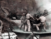 Four soldiers operate a large artillery cannon amidst sandbags and smoke in a rugged outdoor setting—capturing the World War II drama featured in the classic Fighter Attack (1953) DVD.