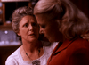 A concerned woman gently touches her friend's shoulder as they stand indoors under warm lighting, evoking a touching moment from "Best Friends for Life (1998) DVD.