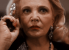An older blonde woman with red lipstick and large earrings holds a gun near her face, dressed in black—an intense moment from Best Friends for Life (1998) DVD, perfect for fans of rare and classic movies on DVD.
