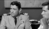 Two men in a black-and-white scene—one in a decorated military uniform speaking seriously, the other in a white shirt with his hand near his face, both at a desk—an ideal image for fans of the "On The Beach (1959) DVD.