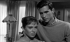 A black-and-white scene from On The Beach (1959) DVD shows a woman with short hair looking anxious as a man stands beside her, both serious in a softly lit room—a striking moment from this classic film.