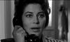 A woman with wavy dark hair holds a phone receiver to her ear, looking concerned—evoking the suspense of classic cinema on the "On The Beach (1959) DVD." The black and white image accentuates her expressive eyes and striking features.