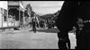 A tense scene unfolds in Terror in a Texas Town (1958) DVD as a lone man walks down a dusty street toward a crowd, while someone in the foreground stands with hand near their gun—capturing classic Western suspense.