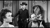 A woman sits in the foreground, looking left. Behind her, a man in a cowboy hat and dark clothes stands, while a bearded man in a robe sits holding a feather—evoking classic Westerns like Terror in a Texas Town (1958) DVD.
