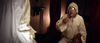 A startled man in old-fashioned nightclothes sits on his bed, facing a mysterious figure in a dim room—capturing the supernatural terror of "Haunted Hotel (2021)" DVD.