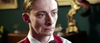 A young man with slicked-back hair and pale skin, dressed in a white shirt, red sweater vest, and brown bow tie, stands in a warmly lit room—evoking the eerie mood of "Haunted Hotel (2021) DVD.