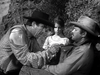 A tense moment from a black-and-white Western shows one man gripping another’s shirt as a concerned young girl watches. All three wear classic Western attire, reminiscent of Anthony Quinn in The Ride Back (1957) DVD.