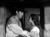 A man in a cowboy hat gently holds a woman's arms as they face each other indoors, both looking serious—a classic black-and-white scene reminiscent of The Ride Back (1957) DVD.