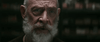 A close-up portrait of an older, bald man with a white beard and piercing blue eyes against a dark background—his intense gaze evokes characters from sci-fi action films like The Tomorrow War (2021) DVD.