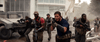 A squad of armed soldiers in tactical gear advances cautiously outside a sleek glass building amid smoke and debris—a thrilling moment from The Tomorrow War (2021) DVD.