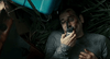 A man with a bruised face lies among grass and debris, holding a walkie-talkie—a gripping moment from the rare sci-fi thriller Timecrimes (2007) DVD.