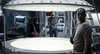 Two men stand in a high-tech lab—one with a tool, the other behind a glowing circular platform, surrounded by control panels. Timecrimes (2007) DVD is ideal for collectors or fans seeking rare sci-fi thriller movies on DVD.