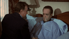 A man in pajamas lies in bed looking unwell with a thermometer, as another man in a suit speaks to him—evoking scenes from the "Bogie (1980) DVD" classic film, played out in a dimly lit bedroom.