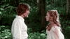 A man and woman in vintage white attire face each other intensely in a green forest, evoking scenes from The Man in the Iron Mask (1977) DVD.