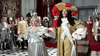 Dressed in elaborate Baroque costumes, a couple dances grandly, recalling scenes from Alexandre Dumas’ story as depicted in The Man in the Iron Mask (1977) DVD. The man sports gold with red feathers; the woman dazzles in silver and an ornate headpiece.