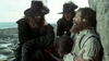 Three men in dark, old-fashioned clothing stand by the sea; one kneels, leaning against a bearded man in light clothes slumped by a stone wall—evoking scenes from The Man in the Iron Mask (1977) DVD.