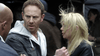 A man in a gray jacket looks concerned as a blonde woman stands beside him, wind catching her hair; another person faces them—evoking a suspenseful outdoor scene from the "Sharknado 2: The Second One (2014)" DVD.