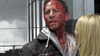 A bloodied man looks anxiously to the side as a blonde woman stands nearby, both against a stormy sky—a dramatic scene from Sharknado 2: The Second One (2014) DVD, now listed among Rare Movies on DVD.