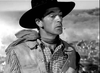 A cowboy in plaid shirt and rugged jacket, cigarette in mouth, gazes sideways in this black-and-white image—capturing classic Western drama. Available on The Westerner (1940) DVD.