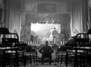A person in a wheelchair faces an empty theater and stage where three performers evoke a classic Western drama, reminiscent of Gary Cooper in "The Westerner (1940) DVD," set in a vintage black-and-white scene recalling Hollywood's golden era.