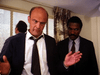 Two men in business suits stand indoors; the one in front gestures as he speaks, echoing intense scenes found in rare DVDs like Courage (1986) DVD—perfect for fans of gripping true crime drama moments.