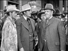 A group of men in vintage Western hats and suits gather in front of a building, evoking a tense scene from classic cinema like the black-and-white West of the Pecos (1945) DVD.