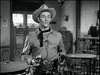 A man in a cowboy hat and western attire stands in a saloon with pistols, evoking classic Western suspense like that in West of the Pecos (1945) DVD.