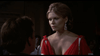 A woman in a red dress with large earrings faces a seated man, her serious look and the dim light evoking the tense mood of World War I air battles from "Von Richthoften vs Brown (1971)" on DVD.