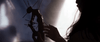 A person with long hair holds a dark, spiky figure under soft side light, casting dramatic shadows and evoking a mysterious mood—reminiscent of a psychological horror film like The Night House (2020) DVD.