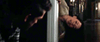 A distressed woman leans backward out of a doorway at night, watched by a concerned man—an eerie scene from the psychological horror film The Night House (2020) DVD, set against blurred background lights.